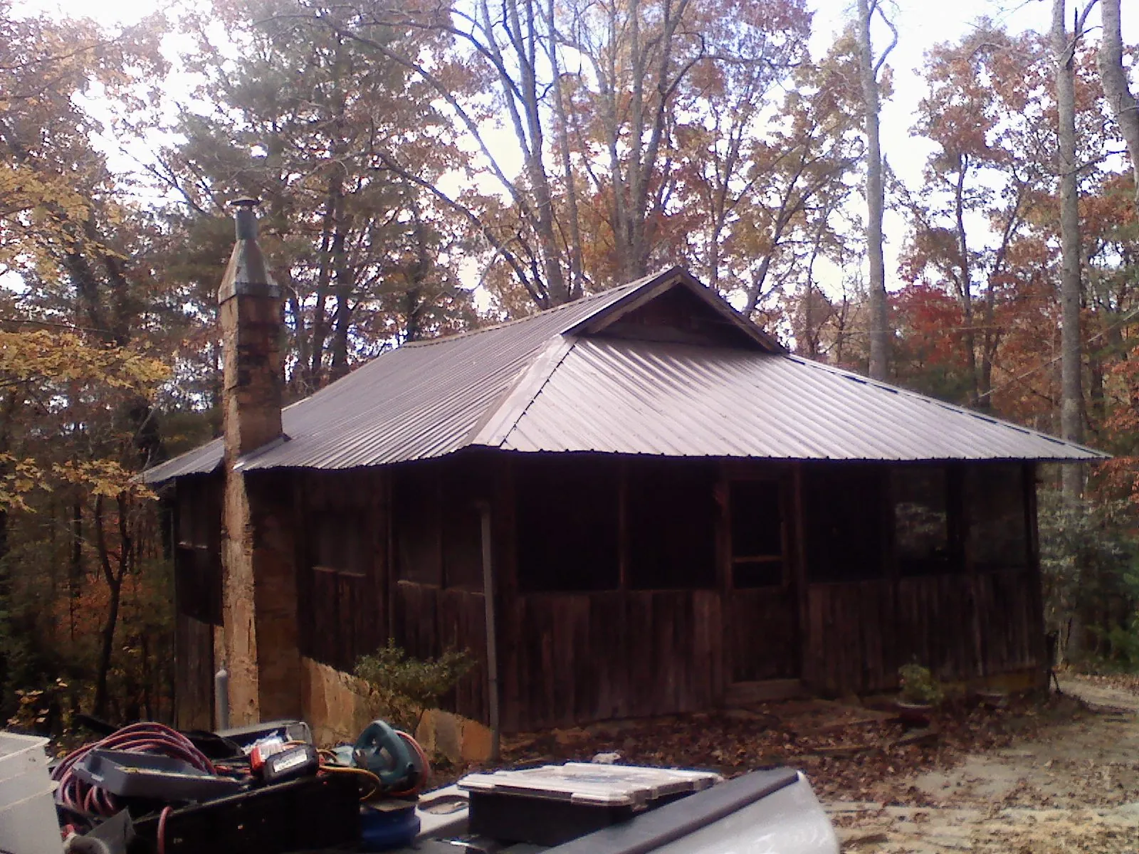Brown metal hip roof on an old cabin with a stone chimney in Quaker Hill