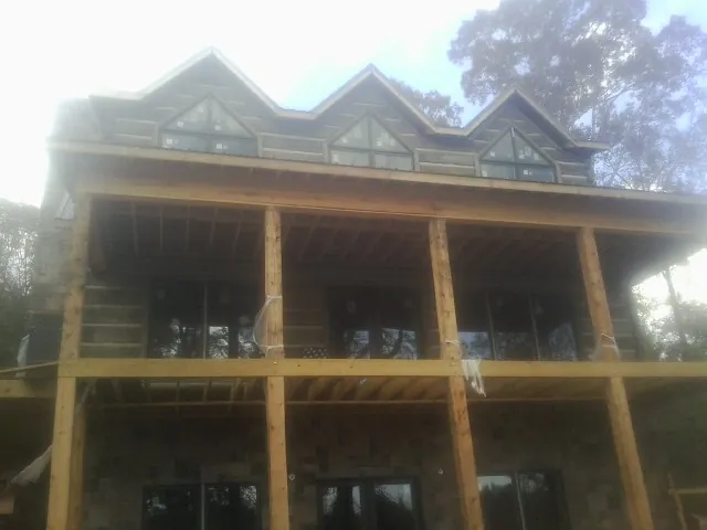 Dormers and porch framing on a large log home under construction — Roof Coating work by our crew in Quaker Hill