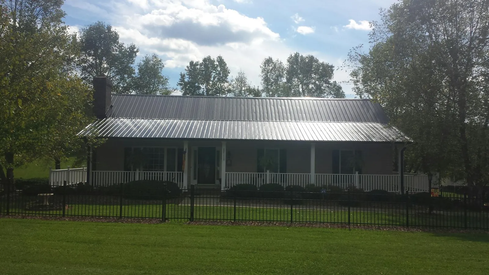 Gray metal roof on a brick ranch with a full width front porch — Gutter Guard Installation work by our crew in Quaker Hill