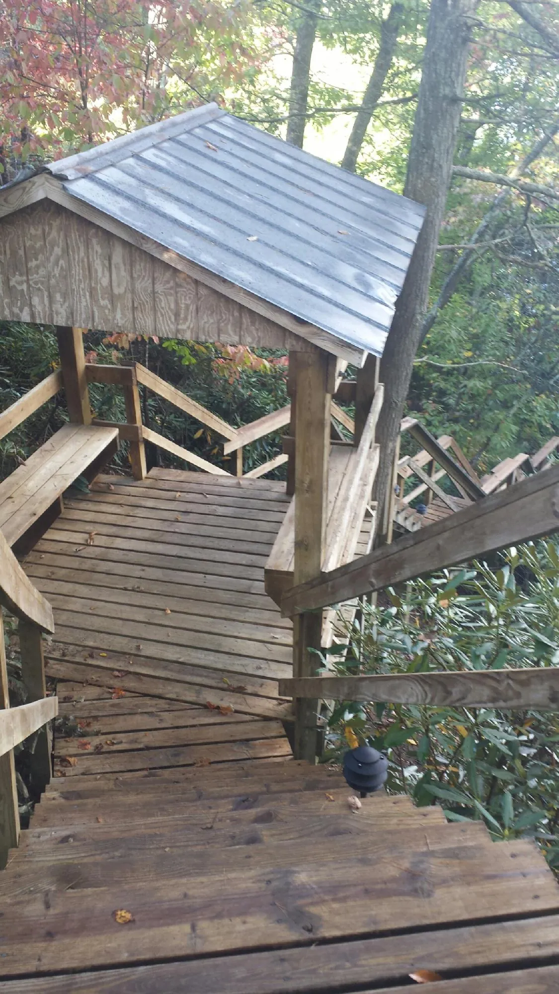 Metal roofed shelter over wooden steps on a wooded walkway — Skylight Repair & Installation work by our crew in Quaker Hill