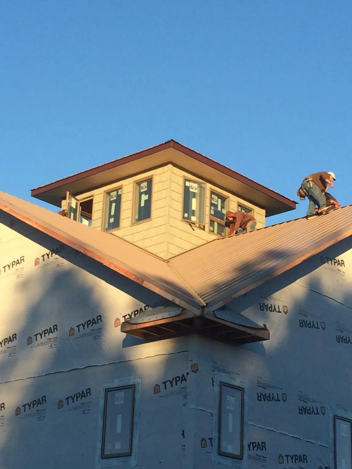 Roofers working around a rooftop cupola on a new metal roof at sunset — Roof Waterproofing in Quaker Hill by Roofing Brothers